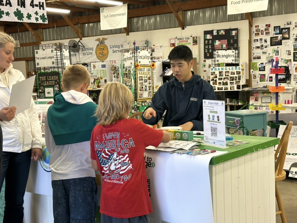 Daniel talking with youth about the Recycle Right activity at the Earth on Us table