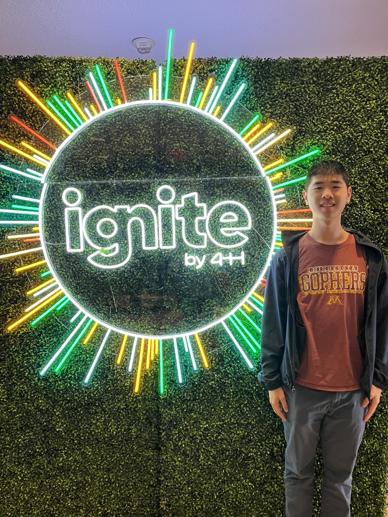 Daniel standing beside the neon Ignite by 4-H sign at the 2026 National Conference in Washington, D.C.