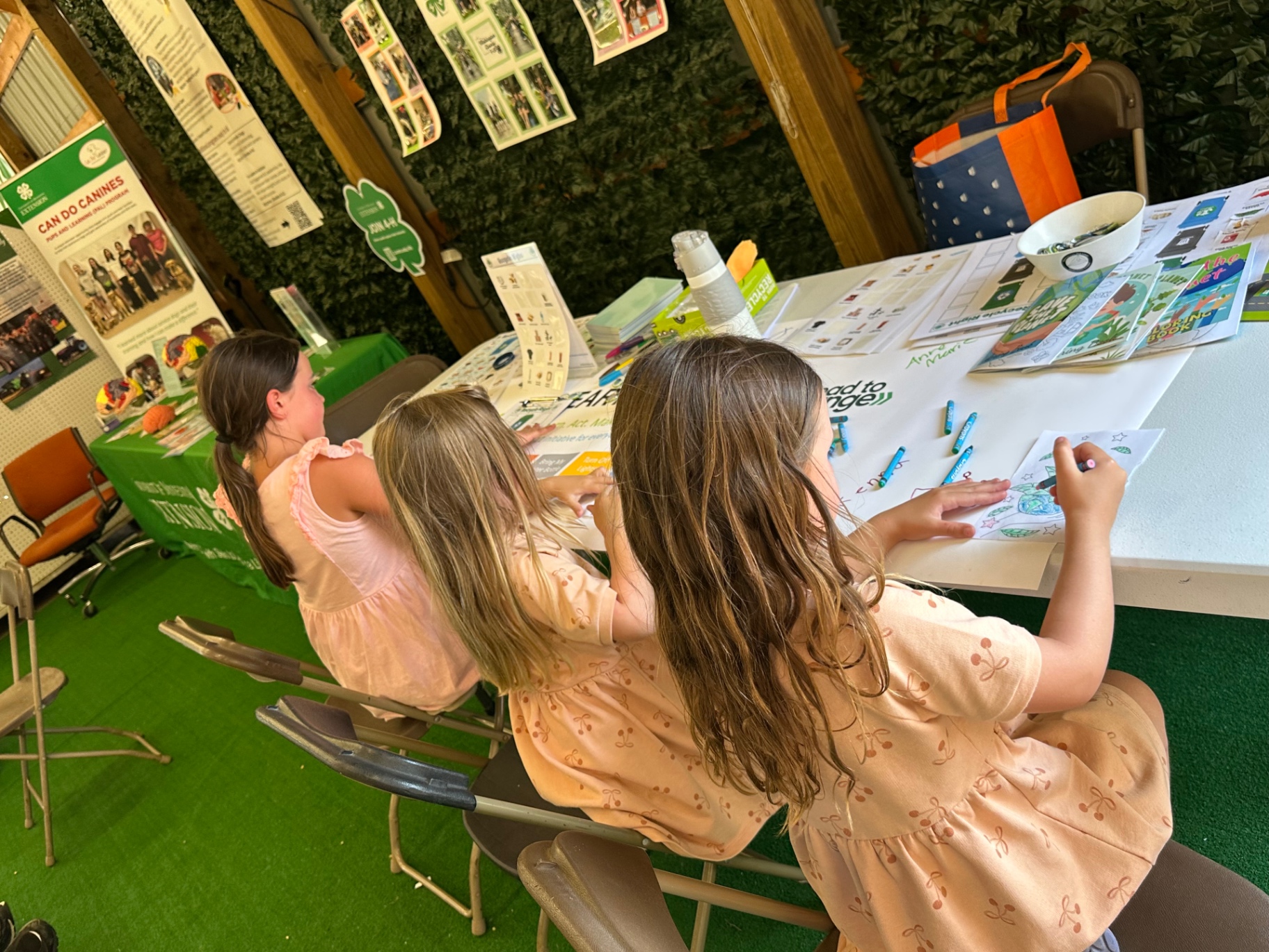 Young visitors coloring Earth on Us activity sheets at the table