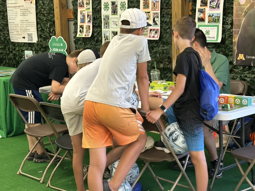 Youth gathered around the Earth on Us activity table in the 4-H Lounge
