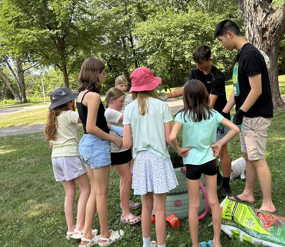 Woodbury 4-H Club members gathered around the recycled tire planter at Carver Lake Park